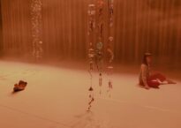 Georgie Goater sitting on a stage with beads hanging