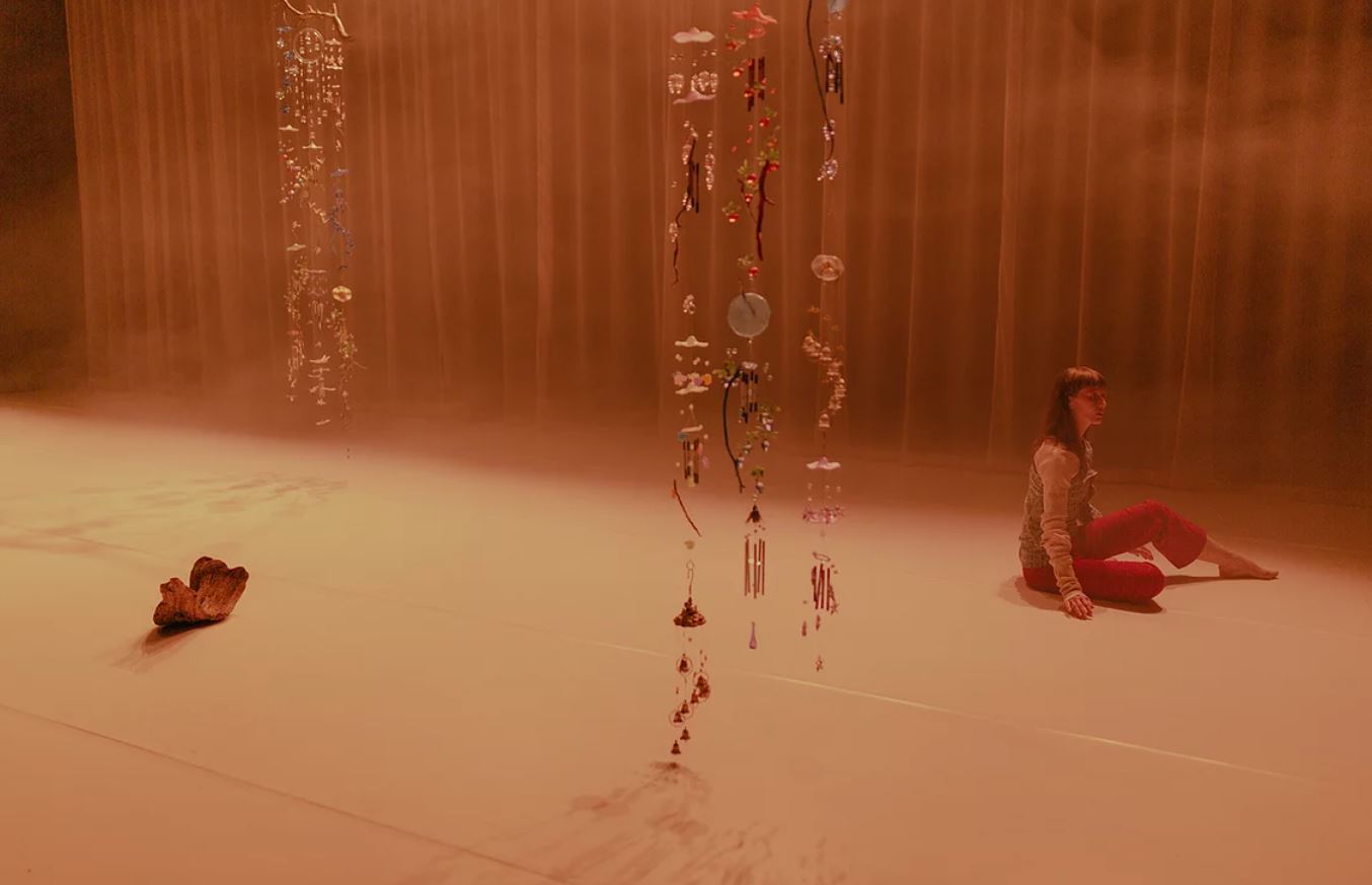 Georgie Goater sitting on a stage with beads hanging