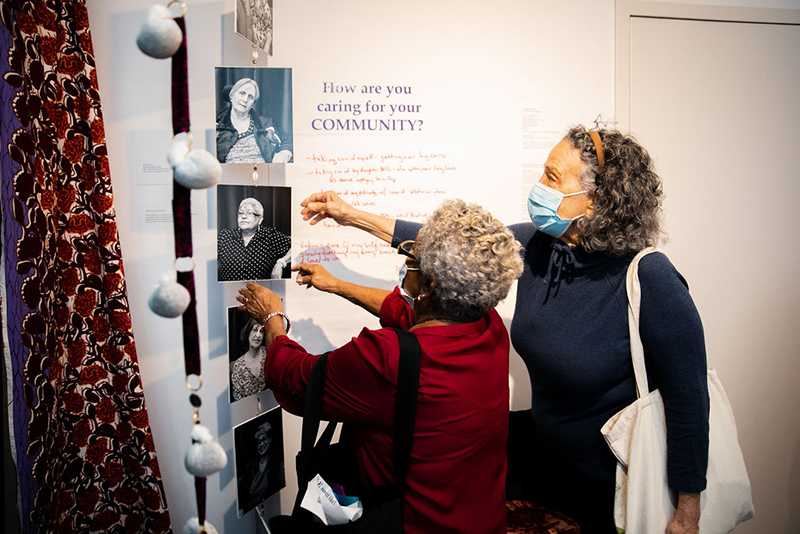 Two people interact with a wall exhibit.