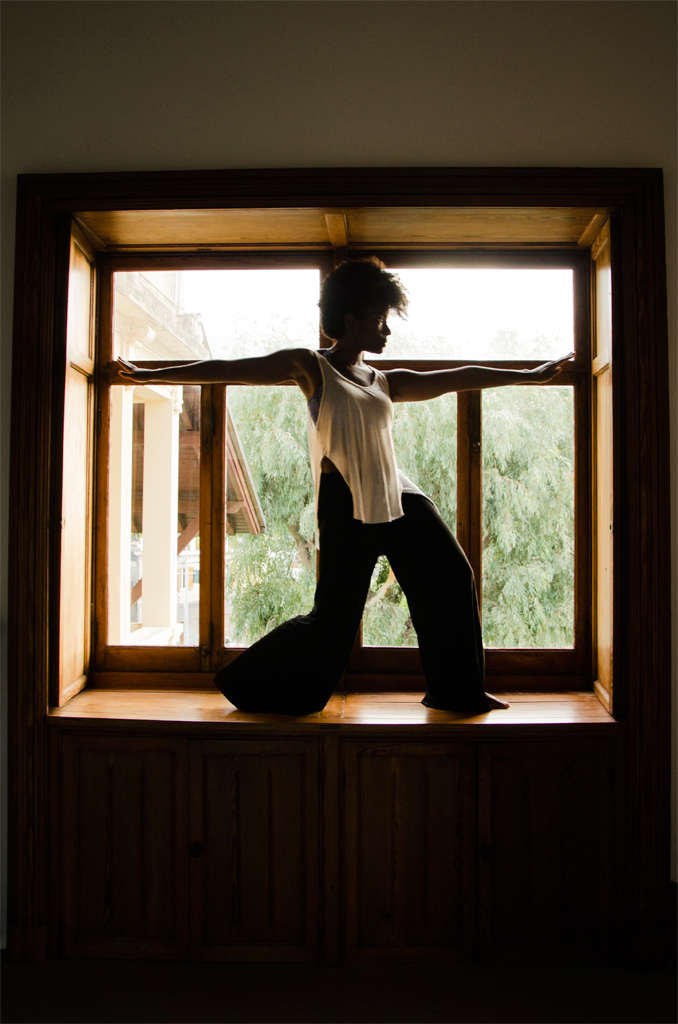 Melanie lunges in silhouette in a window.